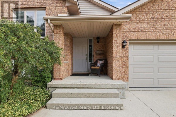 Front porch of a brick house with concrete steps, a door, and a chair. - 194 Norwood Court, Stratford