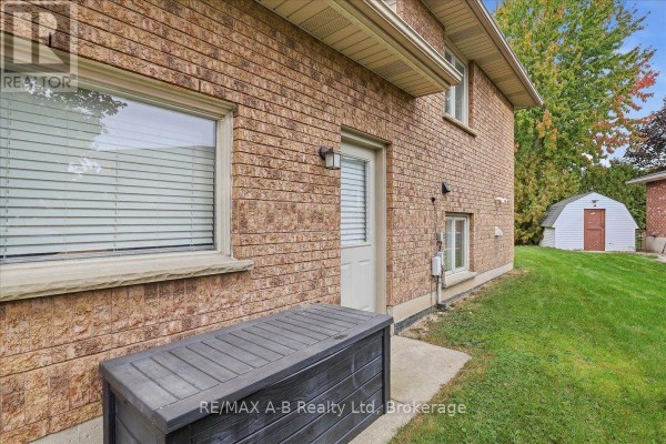 Back view of a brick house with a storage box on a concrete pad and a shed. - 194 Norwood Court, Stratford