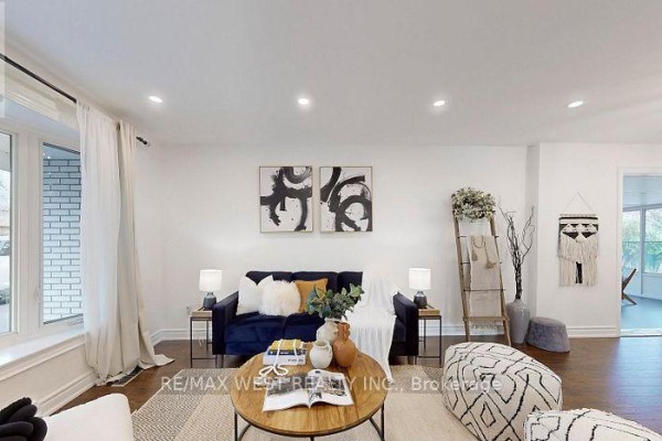 Living room featuring a navy sofa, artwork, and natural light from windows. - 194 Sewell Drive, Oakville