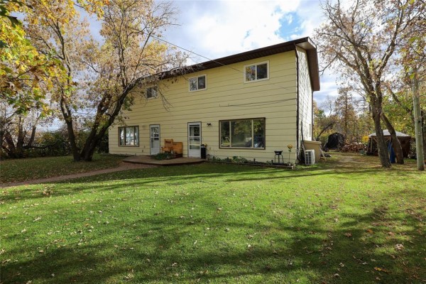 Rear view of a duplex showing windows, doors, and outdoor seating. - 194 St Phillips Drive, Arborg