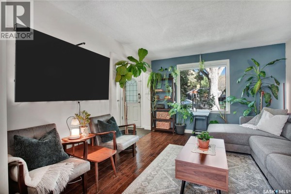 Living room with blue accent wall, large window, grey sectional sofa, and chairs. - 1940 Coy Avenue, Saskatoon
