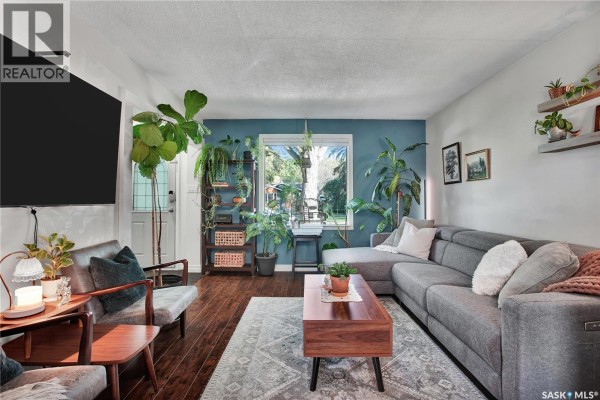 Living room featuring a grey sectional sofa, coffee table, chairs, and large window view. - 1940 Coy Avenue, Saskatoon