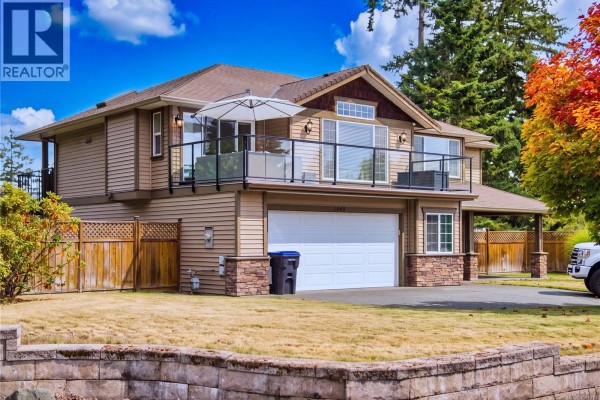 Close-up of the entrance to a beige house with a wooden door and stone-accented columns. - 1940 Legacy Pl, Nanaimo