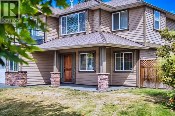 Detail of the garage door and a covered walkway with stone accents on a beige house. - 1940 Legacy Pl, Nanaimo