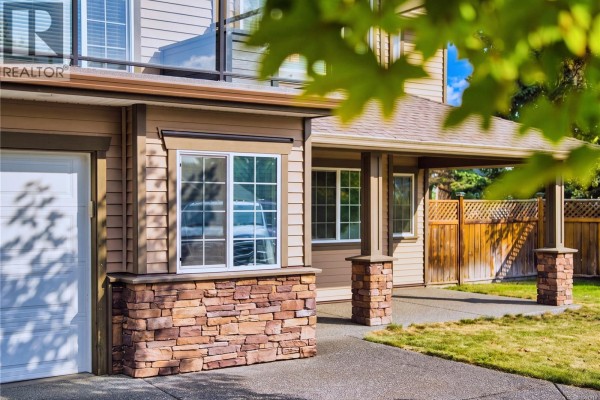 Close-up of the wooden front door with glass sidelights and a covered porch entrance. - 1940 Legacy Pl, Nanaimo