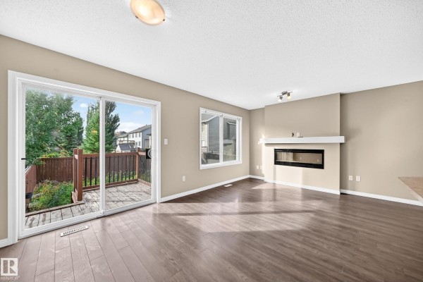A spacious kitchen with dark brown cabinets, stainless steel appliances, and a large island with a sink. - 1941 Chapman Rd Sw, Edmonton