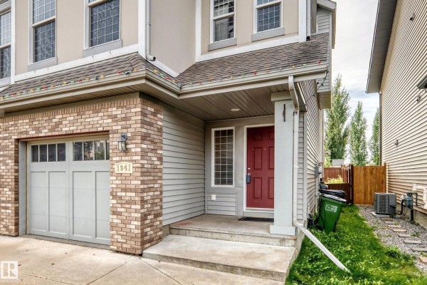 Open concept living and kitchen area with dark brown cabinets, stainless steel appliances, and a large island. - 1941 Chapman Rd Sw, Edmonton
