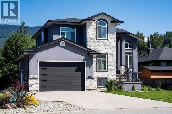 Front exterior of a two-story grey stucco house with a stone facade and attached garage. - 1941 Poplar Lane, Revelstoke