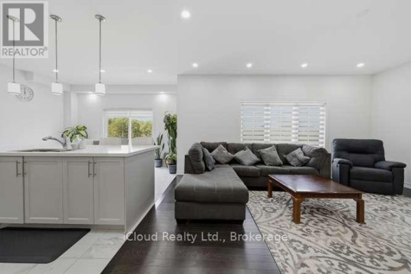 Open concept living and kitchen area with gray cabinets, island, sectional sofa, and wooden coffee table. - 1944 Don White Court, Oshawa