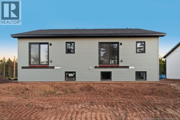 Back of a duplex showing two sliding glass doors, windows, and unfinished landscaping. - 195 Carrington Drive, Riverview