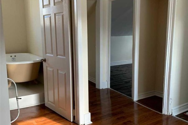 Interior hallway view of a bathroom with a tan clawfoot tub and doorways to rooms. - 195 Division Street, Cobourg
