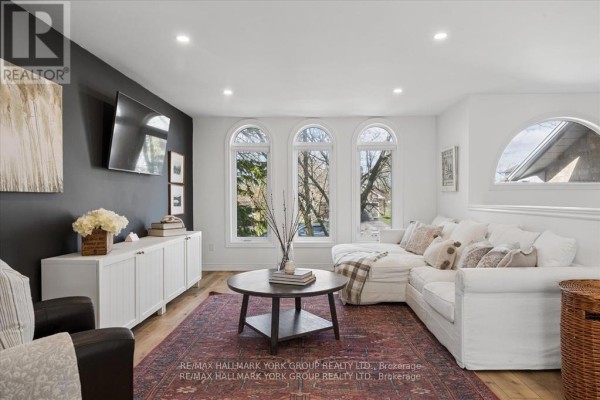 Living room with dark grey accent wall, white sectional sofa, leather chair, and hardwood floors. - 195 King Street, East Gwillimbury