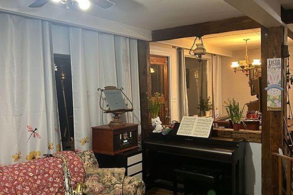 Living room with a piano, floral armchair, and exposed wooden beams. - 195 Lakeland Crescent, Richmond Hill
