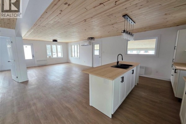 Finished basement with carpeted stairs, utility area, and vinyl plank flooring. - 195 Principale Street, Sainte Anne De Madawaska