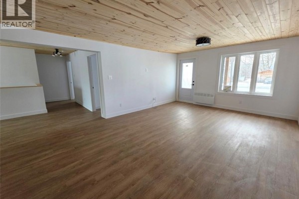 Bedroom with wood-look vinyl flooring, white walls, and doorway to bathroom. - 195 Principale Street, Sainte Anne De Madawaska