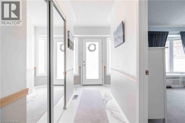 Interior hallway with mirrored closet doors, tiled floors, and a view of the front entrance. - 195 Silverbirch Boulevard, Glanbrook