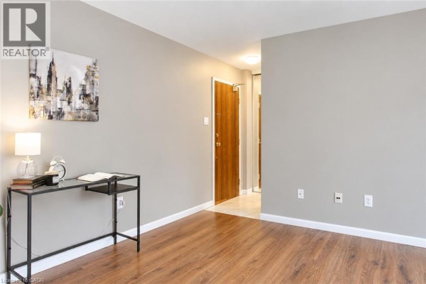 Living room showing a modern desk and hallway entrance with wood doors. - 1950 Main Street Unit# 705, Hamilton