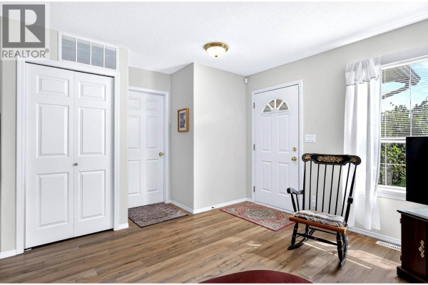 Interior entryway with a rocking chair, double closet doors, and a front door. - 1951 Lodgepole Drive Unit# 21, Kamloops