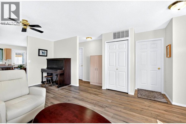 Living room with a piano, double closet doors, and a view into the hallway. - 1951 Lodgepole Drive Unit# 21, Kamloops