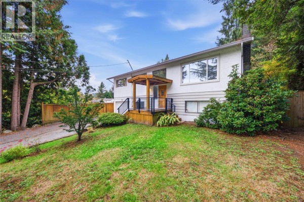Front view of the white, two-story house with a wooden porch and green lawn. - 1951 Szasz Dr, Nanaimo