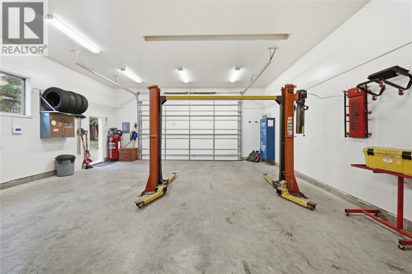 Interior view of the garage, showing two car lifts, tires, and tools. - 1951 Szasz Dr, Nanaimo