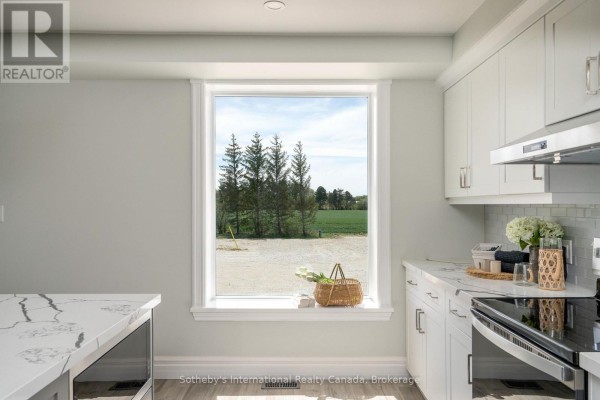 Modern kitchen with white cabinets & marble counters, view of farmland - 1952 Nottawasaga N Clearview