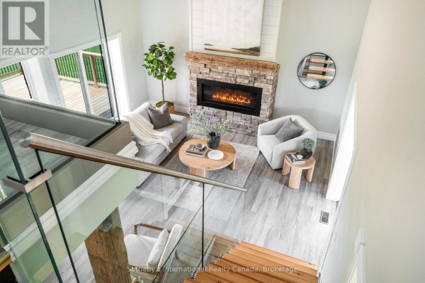 Living room with stone fireplace, modern furniture, and deck view - 1952 Nottawasaga N Clearview