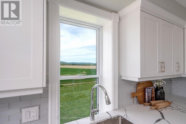Modern kitchen with white cabinets, chrome faucet, and scenic countryside view - 1952 Nottawasaga N Clearview