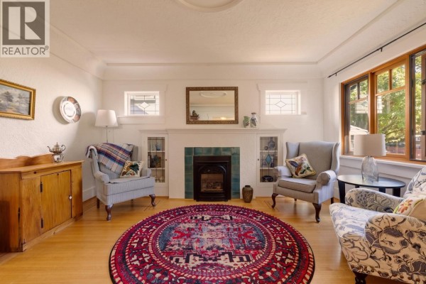 Living room with two armchairs, a patterned rug, a fireplace, and hardwood floors. - 1955 E 8th Avenue, Vancouver