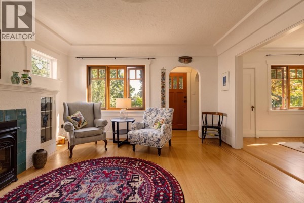 Living room fireplace with teal tile surround, decorative mirror, and glass-fronted cabinets. - 1955 E 8th Avenue, Vancouver