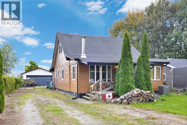 Side view of the house with a gravel driveway leading to a detached garage. - 1957 Front Road North, Amherstburg