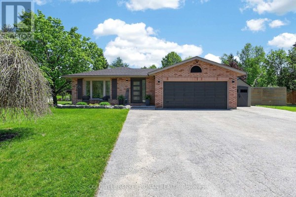Brick bungalow with a dark grey garage door and a paved driveway. - 1959 Snow Valley Road, Springwater