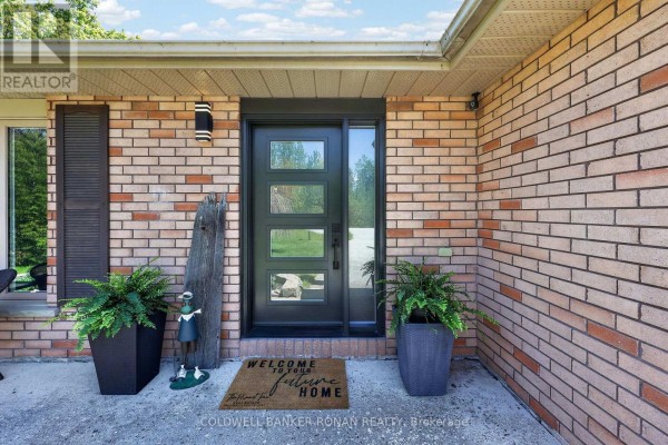 Close-up of the front door with glass panels and surrounding brick. - 1959 Snow Valley Road, Springwater