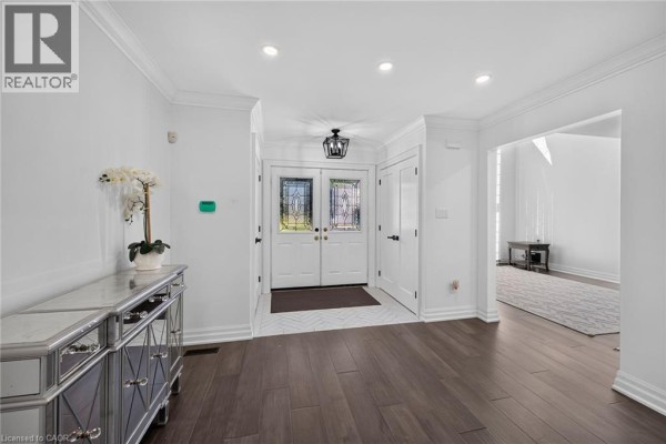 Interior foyer with dark hardwood floors, white walls, and a mirrored console table. - 196 Bluebell Crescent, Ancaster