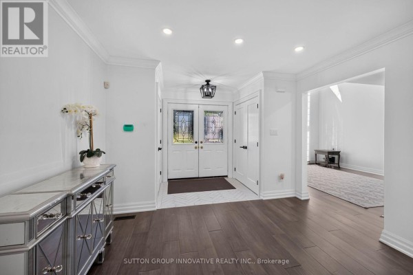 Wide angle of the foyer with white walls, glass front doors, and a mirrored console table. - 196 Bluebell Crescent, Hamilton