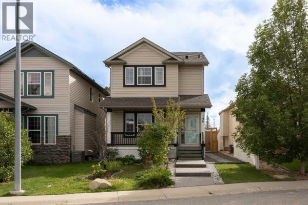 Front exterior of a two-story beige house with a dark porch, situated on a lawn with a paved walkway. - 196 Eversyde Circle Sw, Calgary