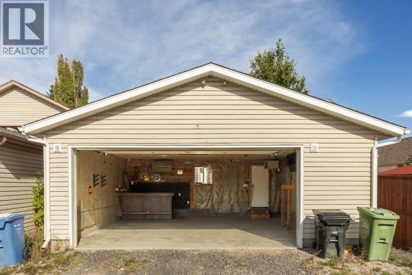 Interior view of an unfinished garage with a bar area, hot tub, and an open garage door. - 196 Eversyde Circle Sw, Calgary