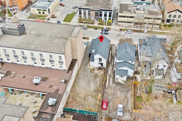 Gravel parking lot behind the white commercial building with a wooden fence. - 196 King Street, St  Catharines