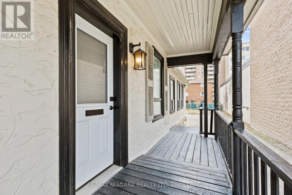 Interior room with grey walls, hardwood floors, a small kitchen area, and white door. - 196 King Street, St  Catharines