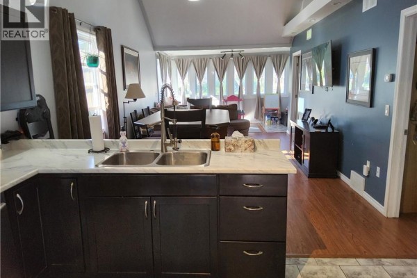 Kitchen island with double sink and faucet, facing an open-concept dining and living area. - 196 North Main Street, Simcoe