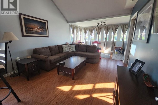 Living room with a large sectional sofa, coffee table, and floor-to-ceiling windows with curtains. - 196 North Main Street, Simcoe