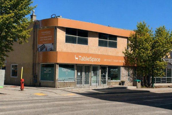 Side view of the tan commercial building with various signage and windows. - 196 Osborne St, Winnipeg
