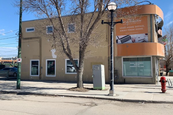 Rear view of the building showing a paved parking lot with several cars. - 196 Osborne St, Winnipeg