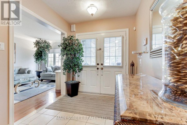 Interior foyer with double doors, a mirrored console table, and a view into the living room. - 196 Wainscot Avenue, Newmarket