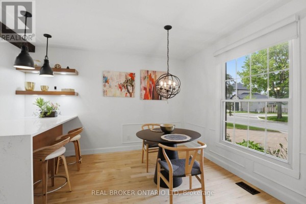Open dining area with round table, pendant light, and view into the kitchen. - 196 Wychwood Park, London North
