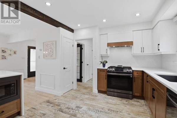 Kitchen area with modern appliances, wooden accents, and bar seating overlooking dining area. - 196 Wychwood Park, London North