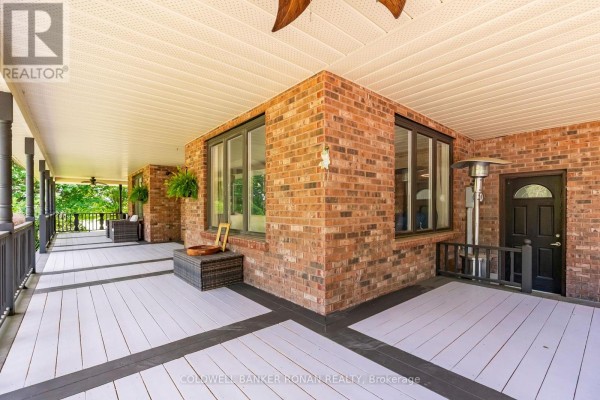 View of the spacious wrap-around porch with white decking, brick walls, and large windows. - 1960 10th Side Road, New Tecumseth