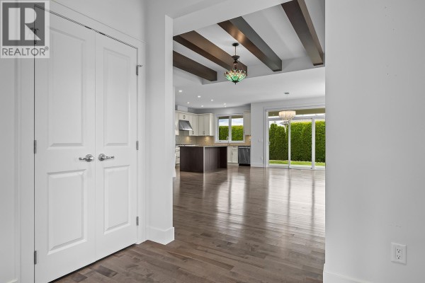 View from entryway into open living space with kitchen, island, and sliding glass doors to backyard. - 1960 Klo Road Unit# 34, Kelowna