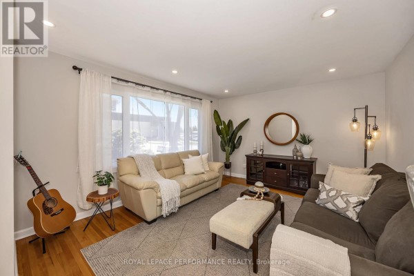 Living room featuring a beige sofa, a dark brown sofa, and a large bay window with sheer curtains. - 1960 Othello Avenue, Ottawa