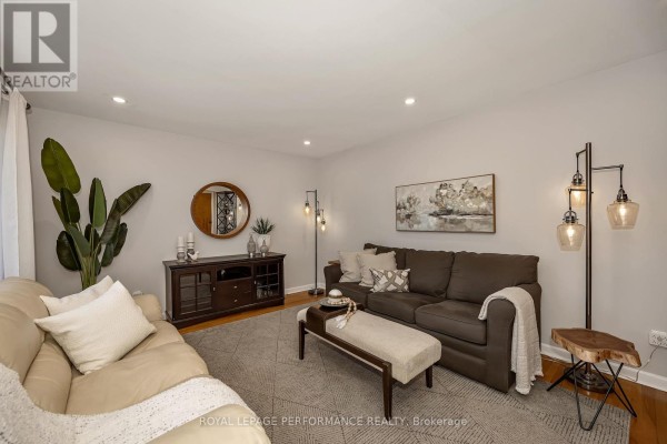 Living room with two sofas, a wooden media console, and decorative floor lamps. - 1960 Othello Avenue, Ottawa